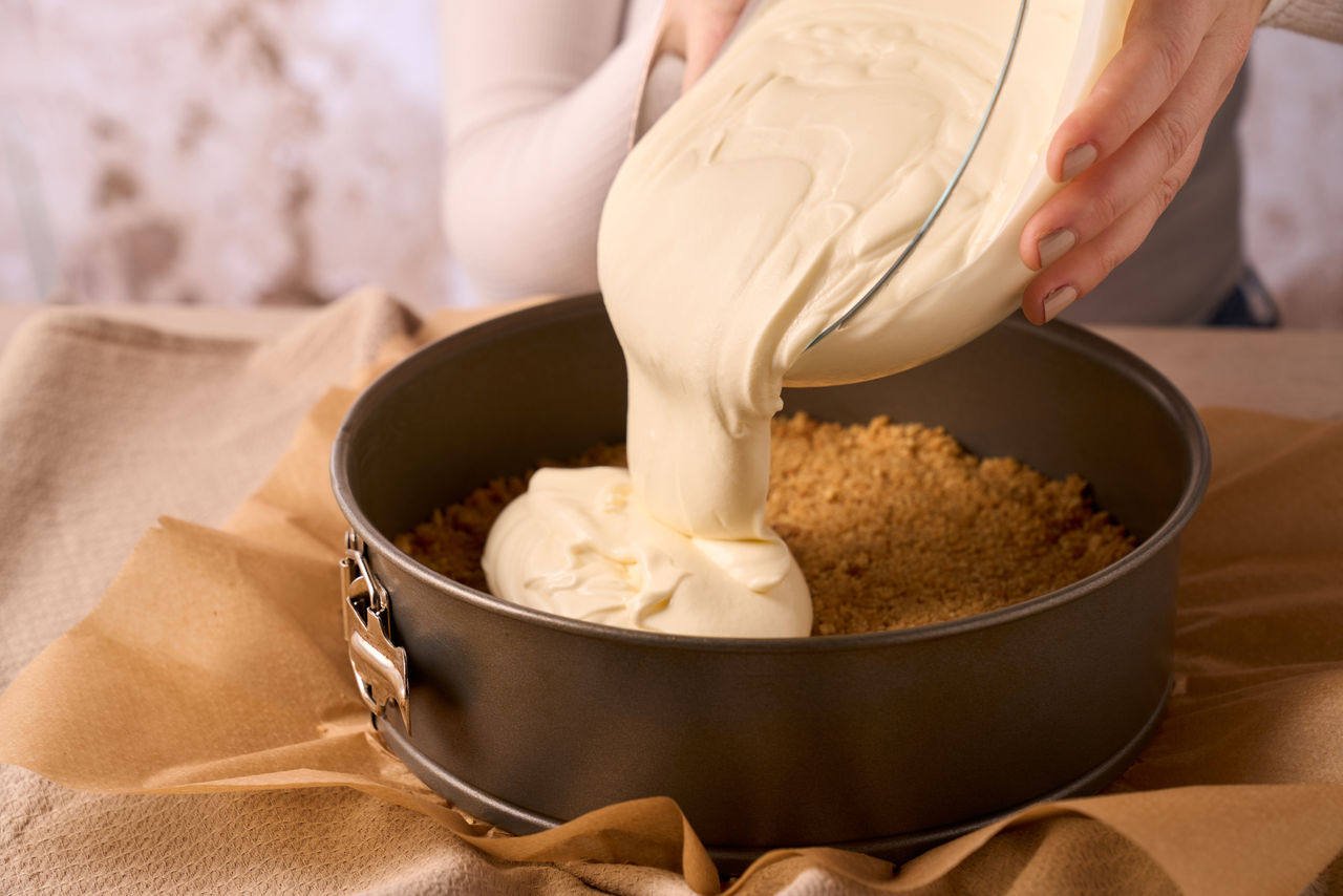 Toppits Backpapier in einer Springform, in die eine cremige Masse gegossen wird.