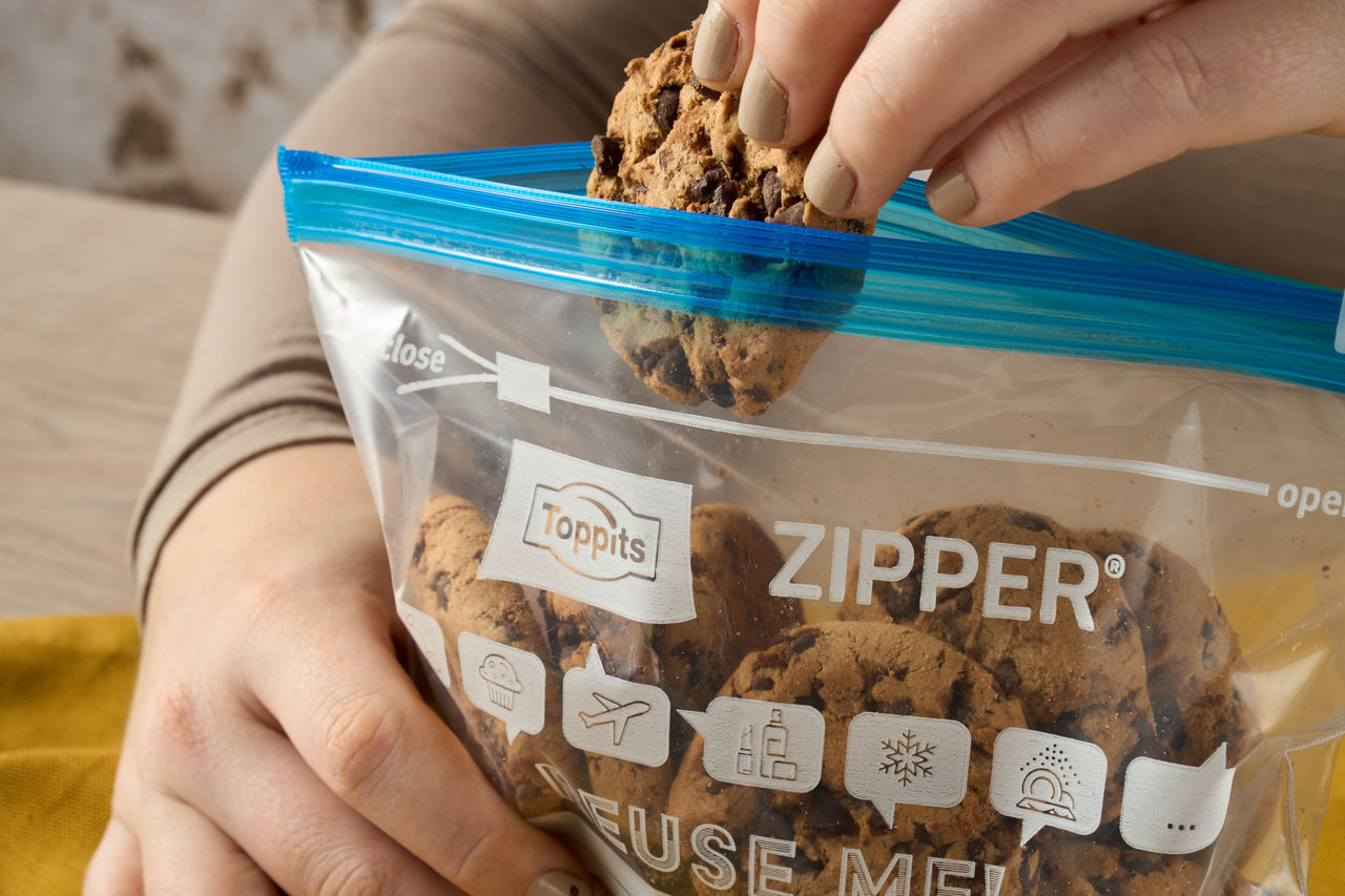 De hand neemt een koekje uit een ritszak